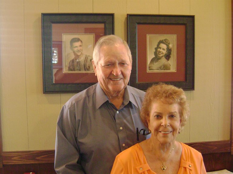 Sonny and Lucille pose in front of pictures of themselves.
