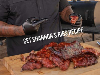 Man points to Baby Back Rib he's holding while multiple racks sit below him, text reads 