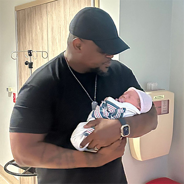 Head Pitmaster Shannon Snell cradling a Baby in a hospital room