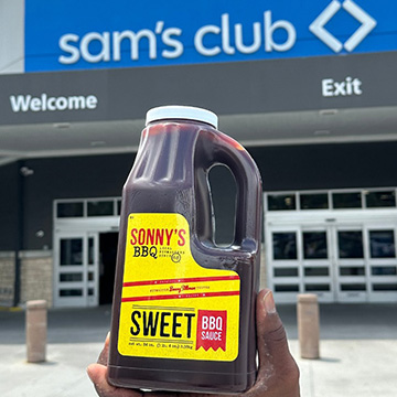 Hand holds 84 oz bottle of Sweet BBQ Sauce in front of Sam's Club
