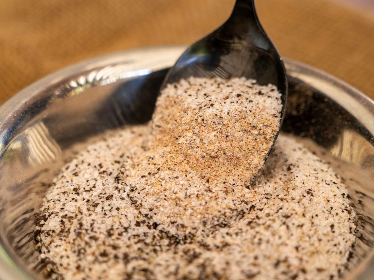 Spoon filled with BBQ rub is being lifted out of bowl filled with more BBQ Rub