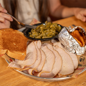 Plate of Smoked Turkey Dinner on Sonny's Table, with a Sweet Potato Green Beans and Garlic Bread,