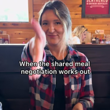 woman holds out hand toward camera while sitting in restaurant, with text reading 