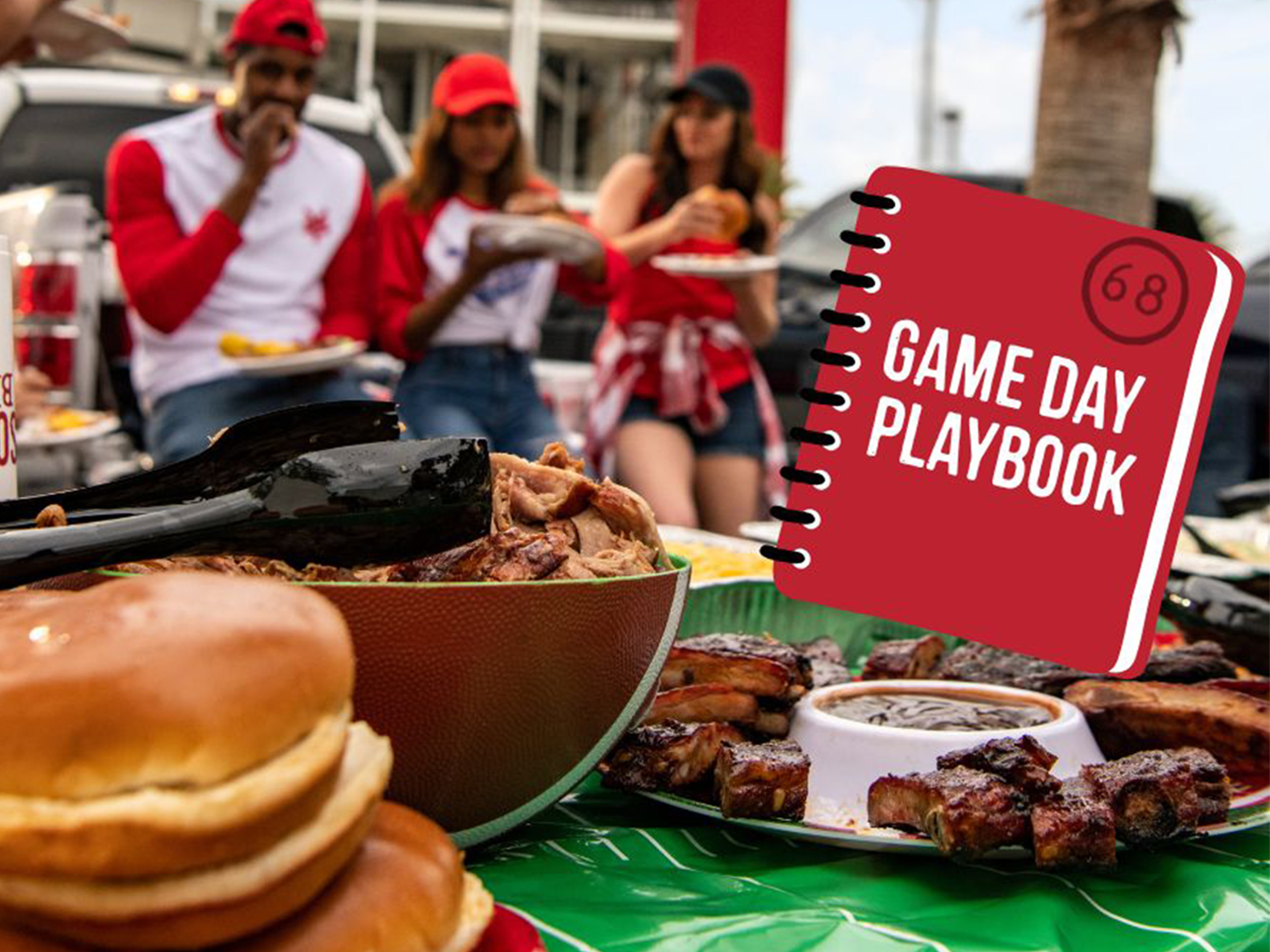 People enjoying BBQ outside football stadium, in front of them is a table lined with BBQ food and football decor. A book is superimposed on top which reads 