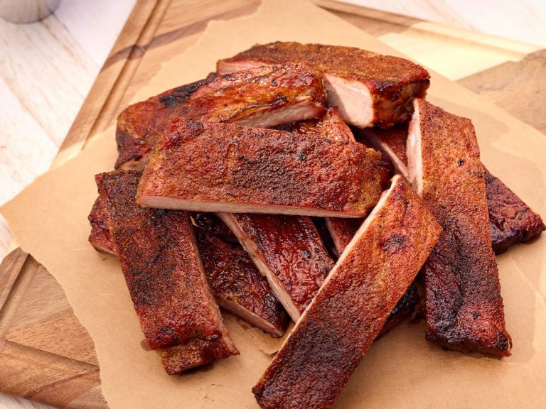 Stack of St. Louis Ribs placed on cutting board, each one seasoned with Dry Rub