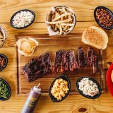 Rack of St. Louis Ribs sits cut on board, surrounded by variety of Sonny's BBQ Sides.