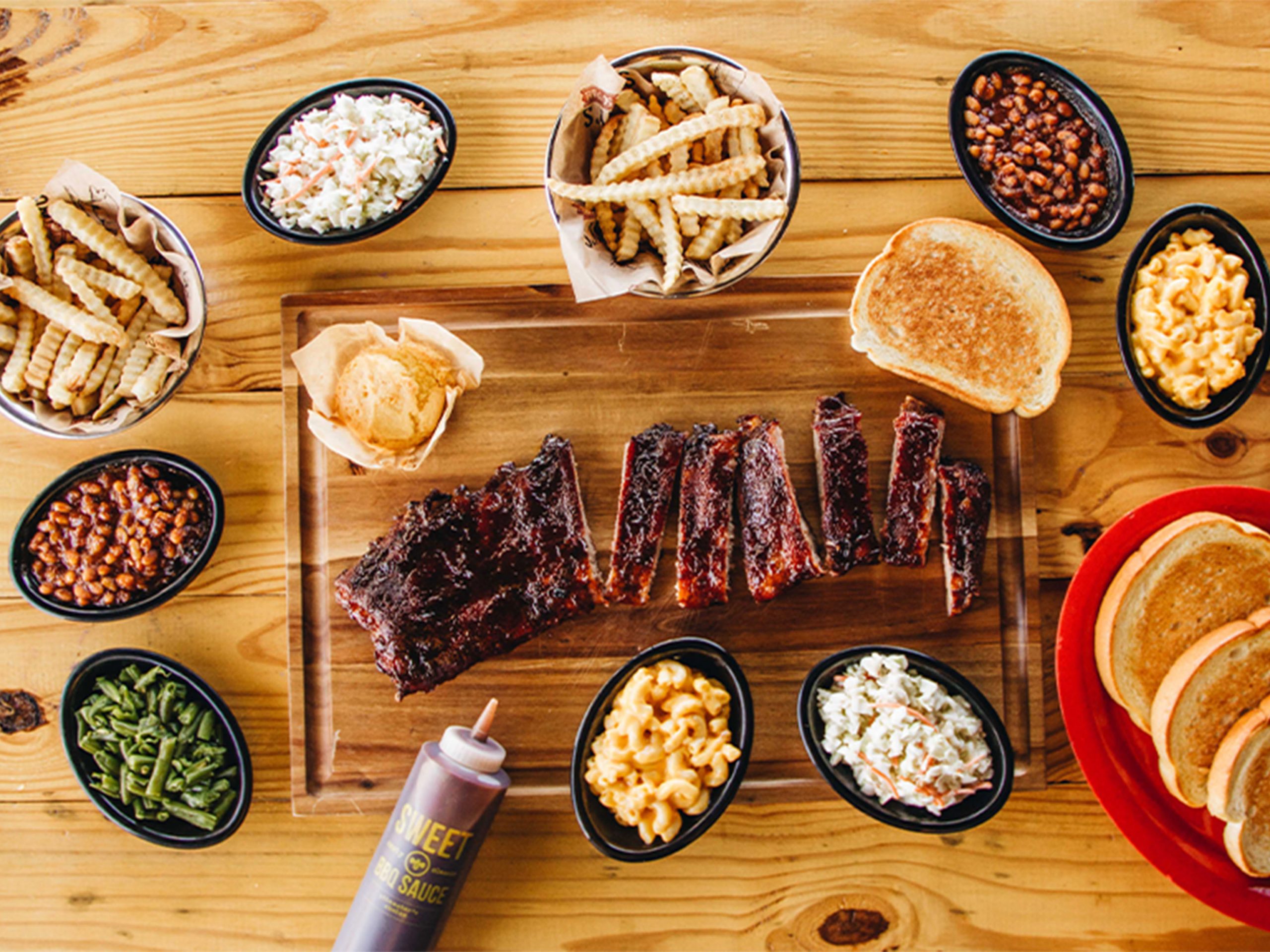 Rack of St. Louis Ribs sits cut on board, surrounded by variety of Sonny's BBQ Sides.