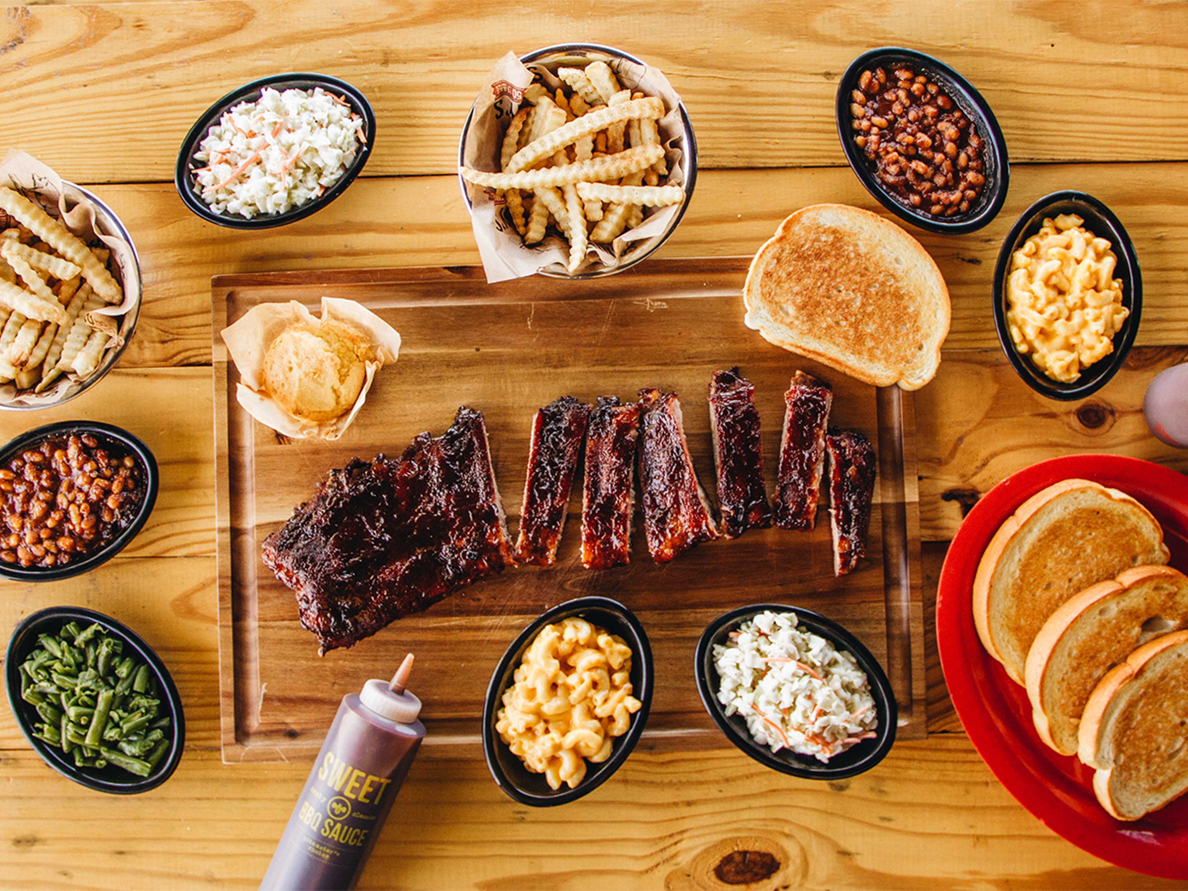 Rack of St. Louis Ribs sits cut on board, surrounded by variety of Sonny's BBQ Sides.