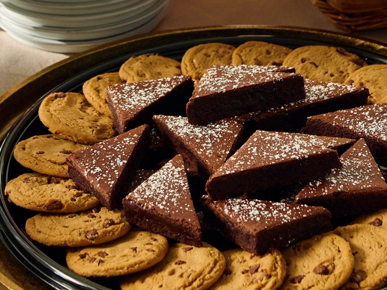 Platter of Cookies and Brownies dusted with cinnamon sugar sits on table, surrounded by plates.