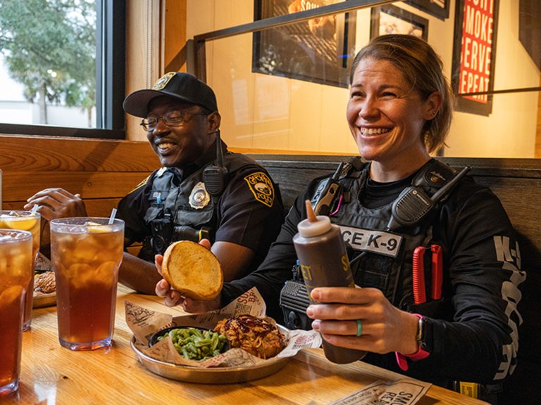 Police officers sit at booth with Pork Big Deals at Sonny's BBQ