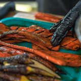 Closeup of carrot slices being brushed with brown sugar and butter mixture.