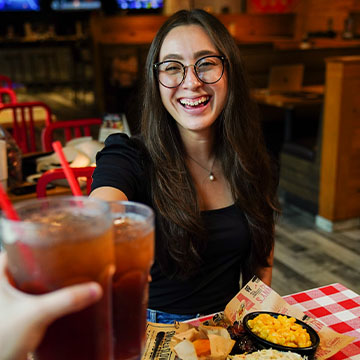Woman cheers with someone off camera with sweet tea