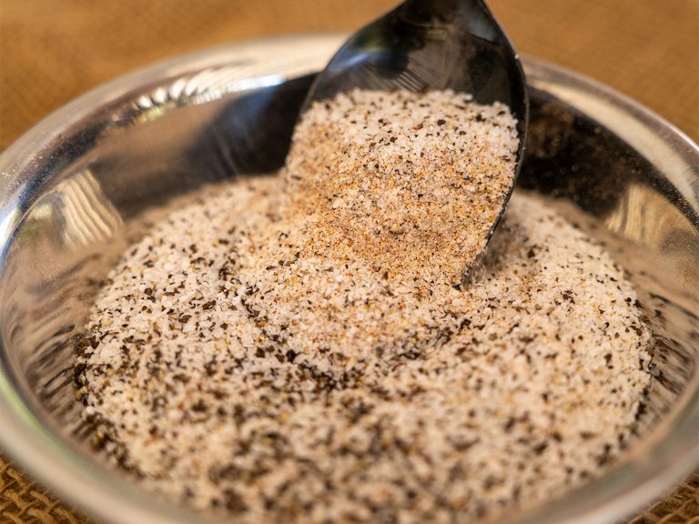 Spoon sits in bowl of basic BBQ rub containing salt, pepper and garlic powder