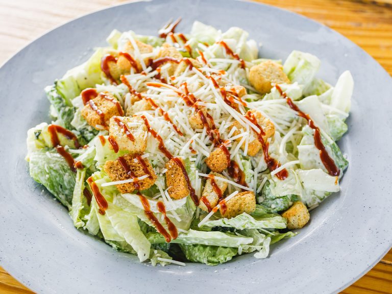 Bowl of Sonny's Smokin' Caesar, without any meat, sits on table.