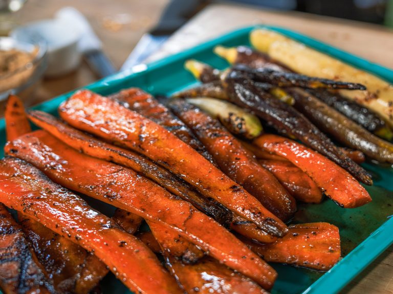 Platter of Honey Glazed Brown Sugar Carrots sits on cutting board.