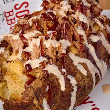 Sonny's loaded bbq potato sits on lined tin