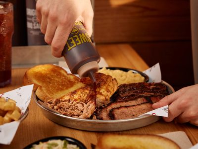 Hand squeezes BBQ Sauce onto Sonny's Sampler, one of Sonny's Originals