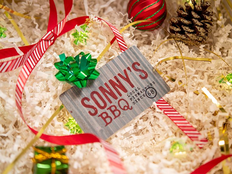 Sonny's Gift Card sits in decorative box filled with paper and holiday decor.