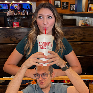 Woman sips Sweet Tea while man holds it up to her in cutout frame