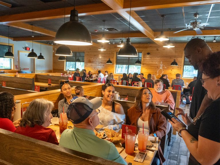 Head Pitmaster Shannon Snell speaks with guests at table at Wesley Chapel Grand Reopening
