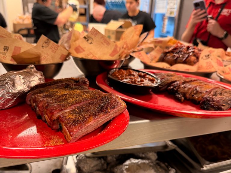Plates full of BBQ ribs, beans and appetizers sit on countertop