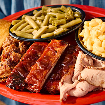 Full plate of Sonny's Pork 3 Ways is held up to camera