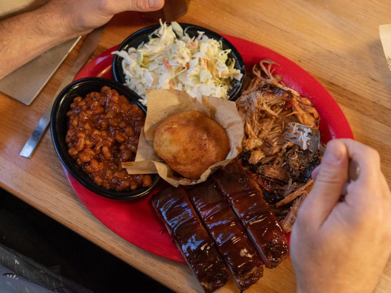 A Sonny's Pick 2 Combo sits on a table, with coleslaw, BBQ beans, pulled pork, St. Louis Ribs and cornbread.
