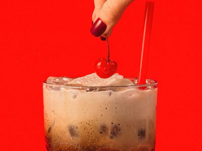 A hand places a cherry on Sonny's Root Beer Cream Soda.