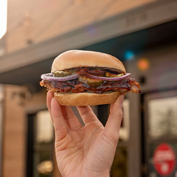 Real Deal Rib Sandwich held up in front of Sonny's building