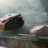 Pitmaster grabs Pork Shoulder from smoker.