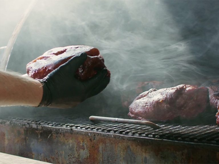 Pitmaster grabs Pork Shoulder from smoker.
