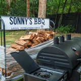 Grill sits next to wood stack that reads 