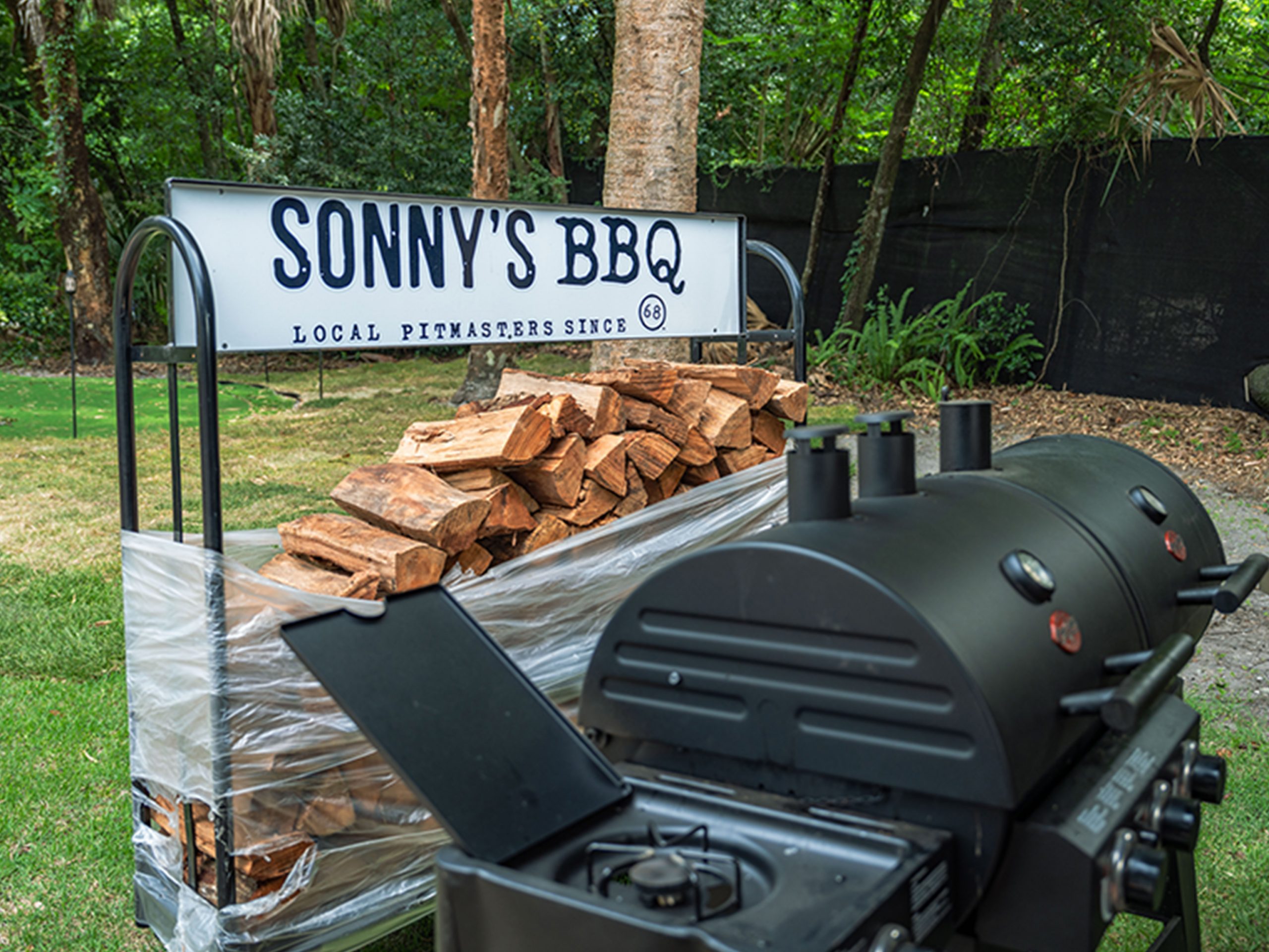 Grill sits next to wood stack that reads "Sonny's BBQ"