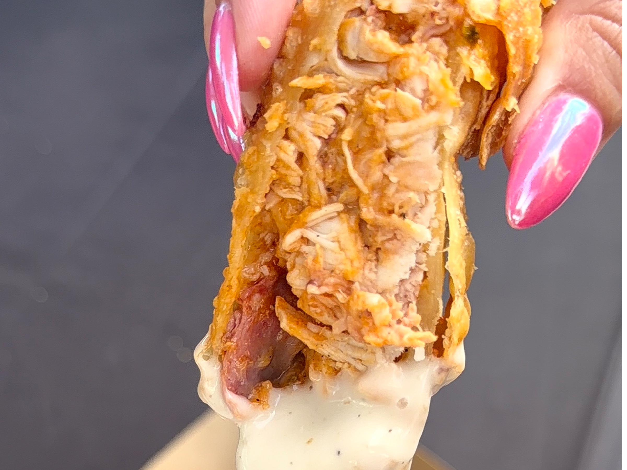 Hand dipping buffalo chicken egg roll in ranch
