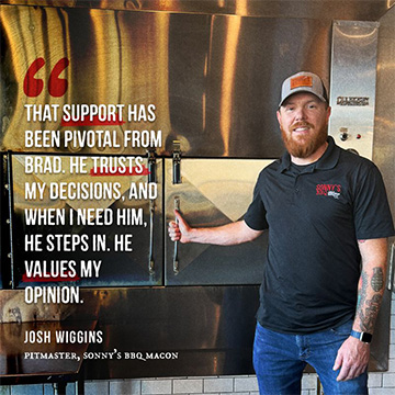 Pitmaster stands proudly in front of smoker with pull quote.