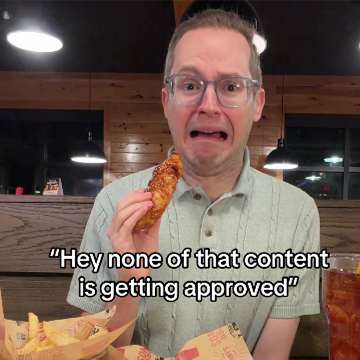 Man looks at camera with chicken tender and a scared look
