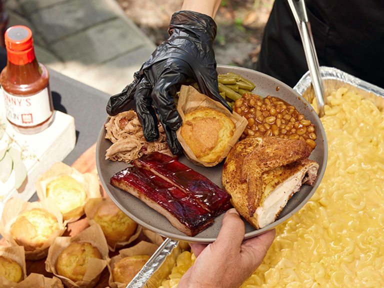 Server places cornbread in middle of packed plate at backyard catering