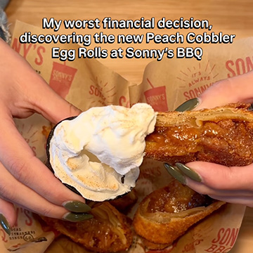 Woman grabs Peach Cobber Egg Roll and dips in whipped cream