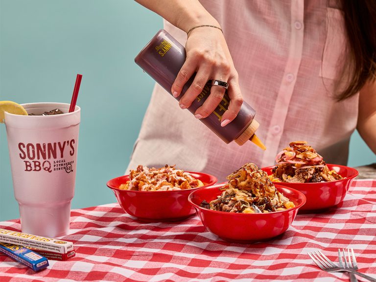 Woman pours BBQ Sauce on BBQ Bowl in table.
