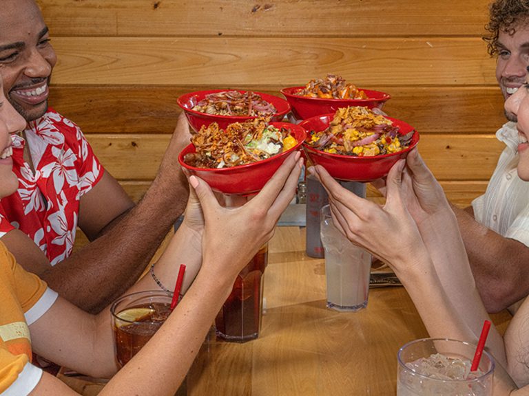 Four friends hold up their BBQ Bowls and smile.