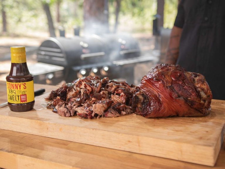 Whole Pork Butt sits next to Pulled Pork and Bottle of Sweet Sauce