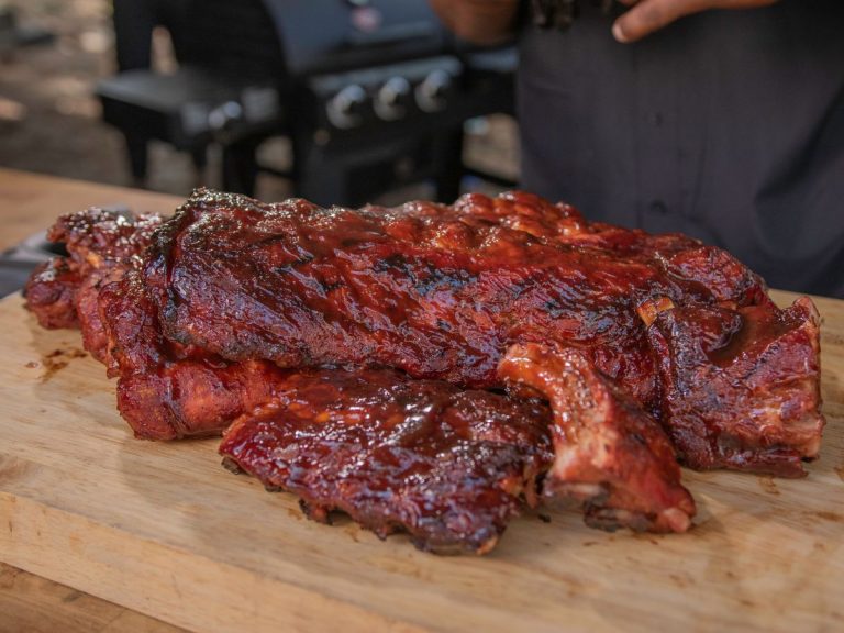 Multiple racks of cooked Baby Back Ribs sit on cutting board