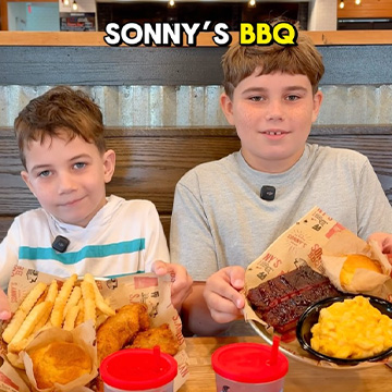 Two kids sit at table with Sonny's BBQ Kids Meals