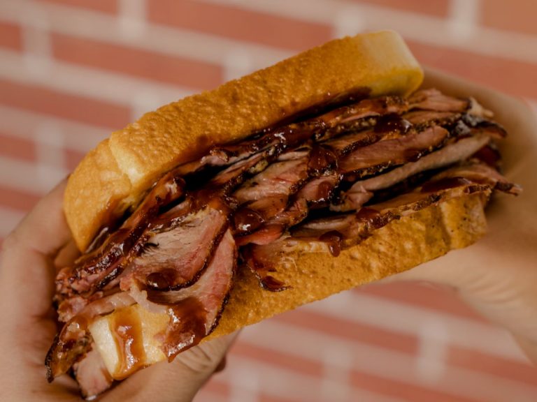 Hands hold a Sliced Pork Sandwich