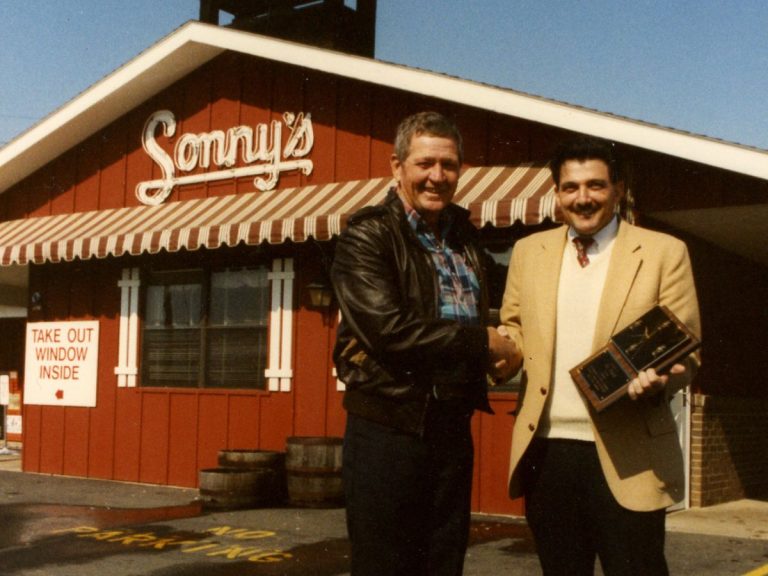 Two men shake hands in front of Sonny's restaurant