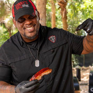 Pitmaster holds Rib and points at it
